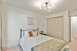 Bedroom with a chandelier, a closet, and light hardwood / wood-style flooring