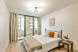 Bedroom with access to exterior, light hardwood / wood-style flooring, and a chandelier