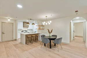 Dining space featuring light hardwood / wood-style flooring, an inviting chandelier, and sink