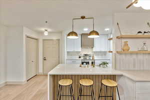 Kitchen featuring a kitchen breakfast bar, sink, hanging light fixtures, light wood-type flooring, and kitchen peninsula