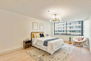 Bedroom with light wood-type flooring, an inviting chandelier, and floor to ceiling windows