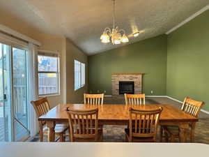 Dining area featuring a textured ceiling, a fireplace, lofted ceiling, and a notable chandelier