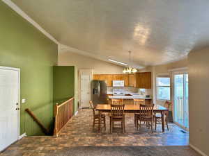 Dining space with a textured ceiling, sink, a chandelier, and vaulted ceiling