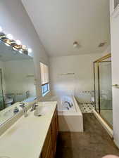 Full bathroom with vanity, independent shower and bath, lofted ceiling, and toilet