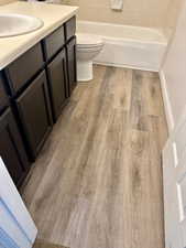 Bathroom with wood-type flooring, vanity, and toilet