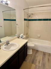 Full bathroom featuring tiled shower / bath combo, toilet, wood-type flooring, and vanity