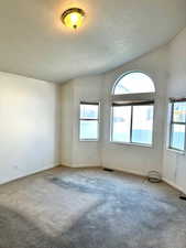 Empty room with light colored carpet and a textured ceiling