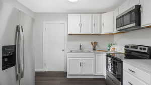 Kitchen with sink, white cabinets, stainless steel appliances, and dark hardwood / wood-style floors