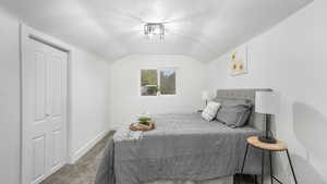 Carpeted bedroom featuring a textured ceiling, a closet, and lofted ceiling