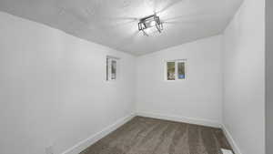 Empty room with carpet flooring, a textured ceiling, and vaulted ceiling