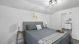 Bedroom featuring a textured ceiling, dark hardwood / wood-style floors, and lofted ceiling