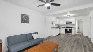 Living room with ceiling fan, wood-type flooring, and sink