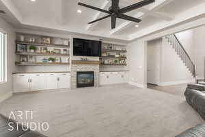 Carpeted living room with a fireplace, beam ceiling, and ceiling fan