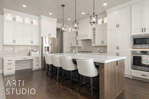 Kitchen with white cabinets, stainless steel appliances, an island with sink, and dark wood-type flooring