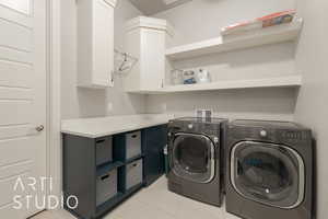 Clothes washing area featuring cabinets, light tile patterned floors, and separate washer and dryer