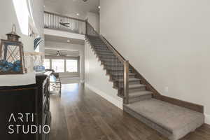 Staircase with wood-type flooring, a towering ceiling, and ceiling fan