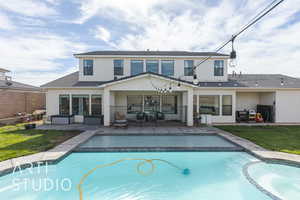 Rear view of property featuring a lawn, outdoor lounge area, a swimming pool with hot tub, and a patio