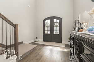 Foyer featuring dark hardwood / wood-style floors, a towering ceiling, and french doors