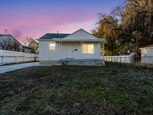 Back house at dusk with a yard