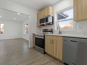 Kitchen featuring sink, stainless steel appliances, light brown cabinetry, and light hardwood / wood-style flooring