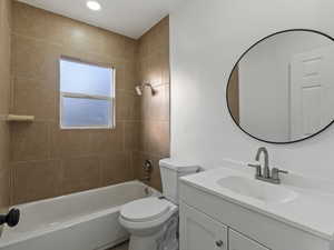 Full bathroom featuring vanity, tiled shower / bath combo, and toilet