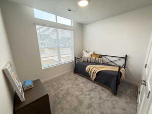 Bedroom with light colored carpet and a textured ceiling