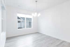 Empty room featuring light hardwood / wood-style flooring and an inviting chandelier