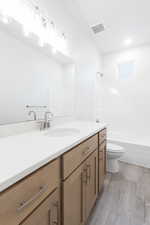 Full bathroom with washtub / shower combination, wood-type flooring, vanity, and toilet