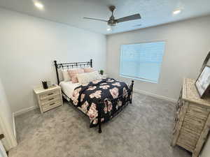 Carpeted bedroom featuring ceiling fan and a textured ceiling