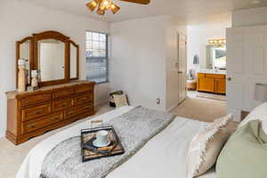 Carpeted bedroom with a closet, connected bathroom, ceiling fan, and sink