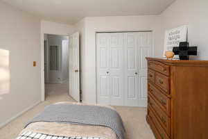 Bedroom featuring light carpet and a closet