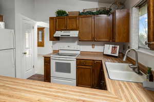 Kitchen featuring wood counters, white appliances, and sink