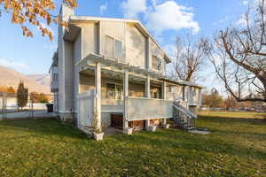 Back of property with a pergola, a mountain view, and a lawn