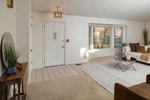 Carpeted entryway featuring a notable chandelier