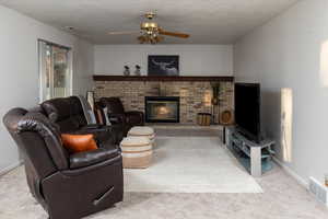 Living room featuring ceiling fan, a fireplace, and light colored carpet