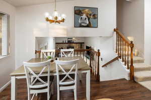 Dining area with ceiling fan with notable chandelier, breakfast area, and dark wood-type flooring