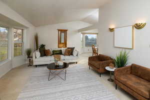 Carpeted living room featuring lofted ceiling and a wealth of natural light