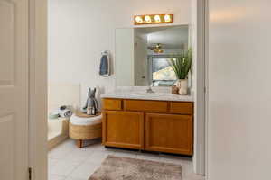 Bathroom with ceiling fan, tile patterned flooring, vanity, and a bath