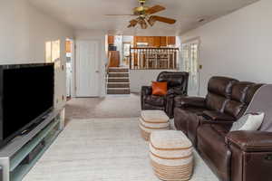 Carpeted living room featuring ceiling fan