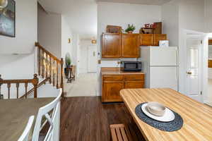 Kitchen with white fridge, a high ceiling, and dark hardwood / wood-style floors