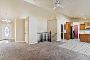 Open concept with light carpet, and vaulted ceiling