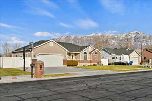 Single story home featuring a mountain view, a front yard, and a garage