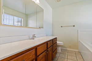 Bathroom featuring tile patterned flooring, a bath, vanity, and toilet