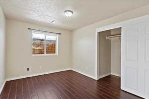 Unfurnished bedroom featuring a closet, wood-style tile flooring, and a textured ceiling