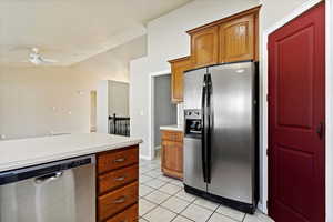 Kitchen featuring appliances with stainless steel finishes, light tile patterned floors, vaulted ceiling, and ceiling fan