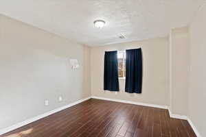 Spare room featuring a textured ceiling and dark wood-style tile flooring