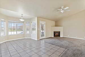 Open concept dinning and living room featuring ceiling fan, light tile patterned floors, and lofted ceiling