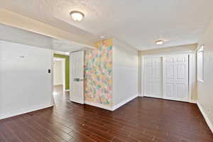 Spare room featuring a textured ceiling and dark wood-style tile flooring