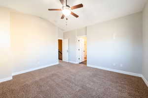 Carpeted spare room featuring ceiling fan and vaulted ceiling