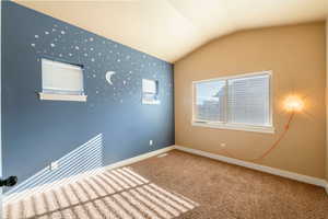 Unfurnished room featuring carpet flooring and vaulted ceiling